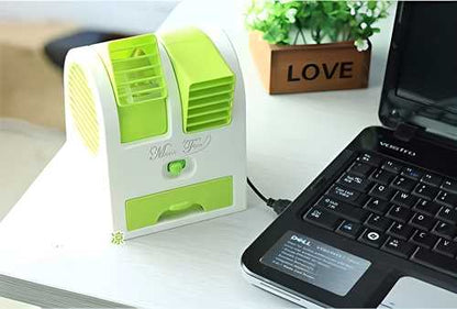 Small green and white portable air conditioner on a desk next to a laptop